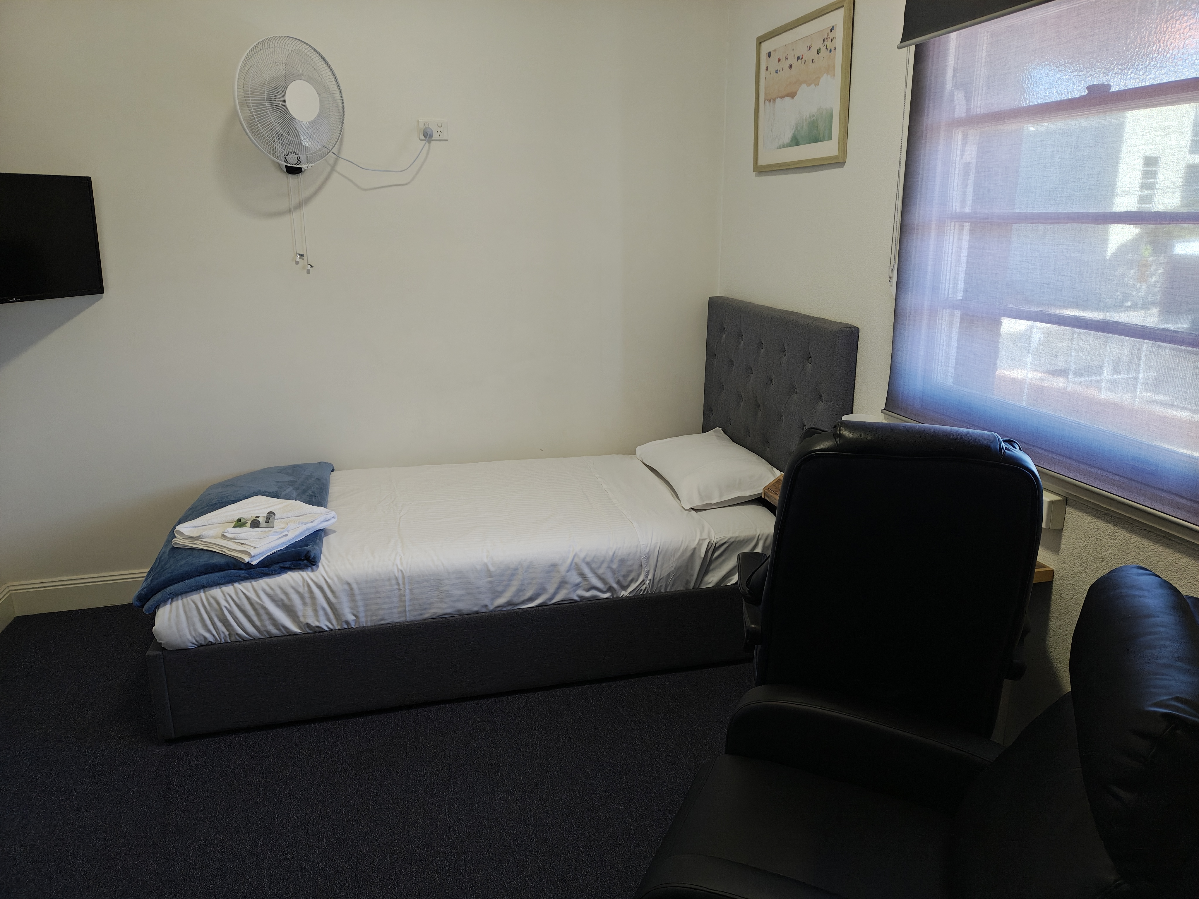 Freshly prepared single guest room with smart TV and seating