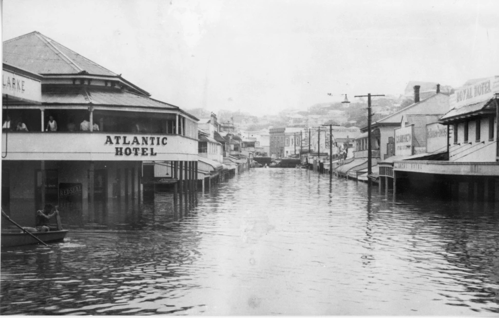 Mary Street, Gympie under flood in 1955 with a man rowing past the Royal Hotel