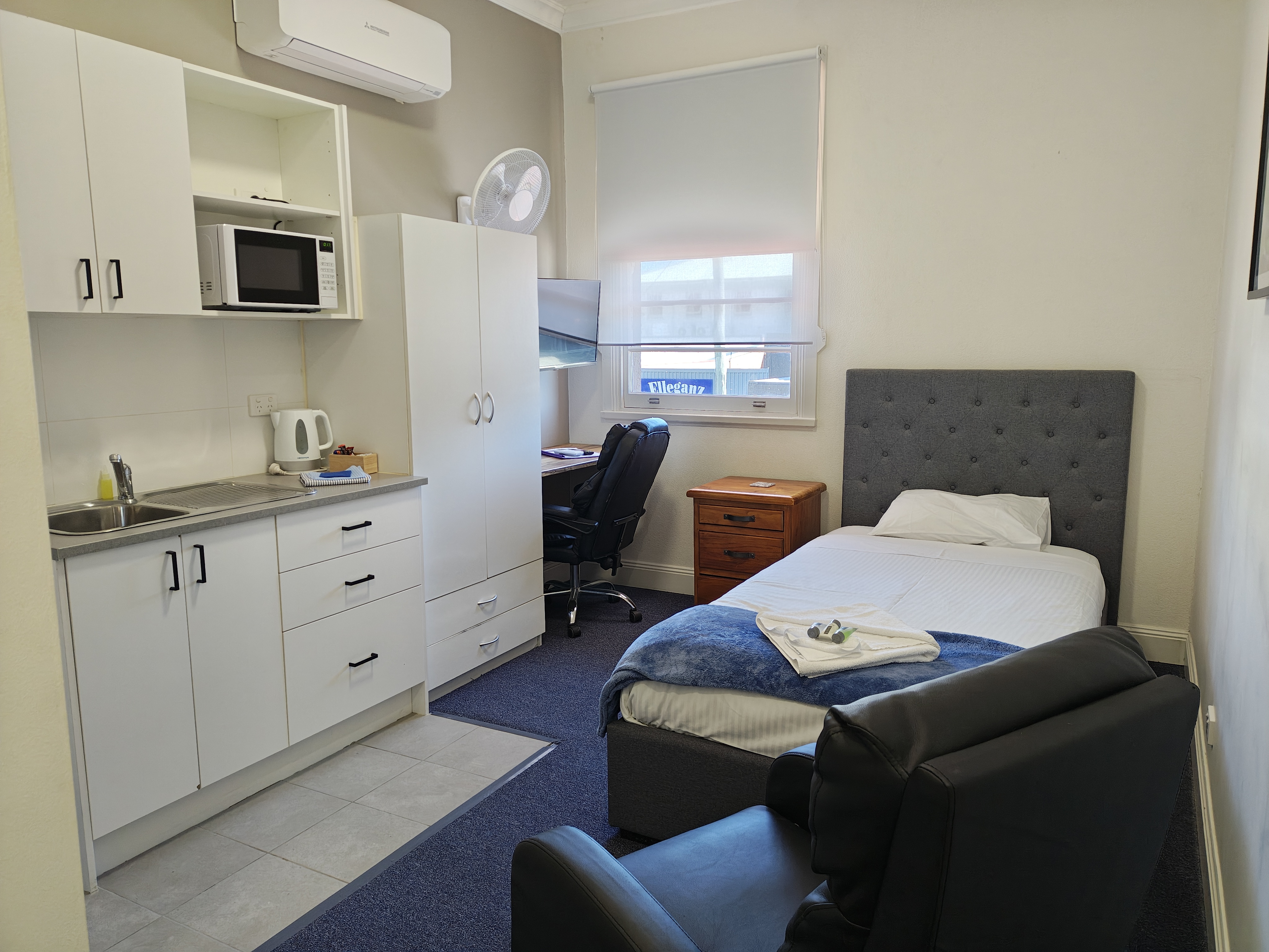Premium Room 20 with a single bed, kitchenette, workspace, and lounge seating
